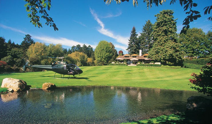 Huka Lodge Central North Island helicopter landing on a lawn near a lodge 