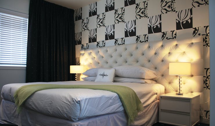Regent of Rotorua Central North Island suite bedroom with white headboard and black and white patterned wallpaper