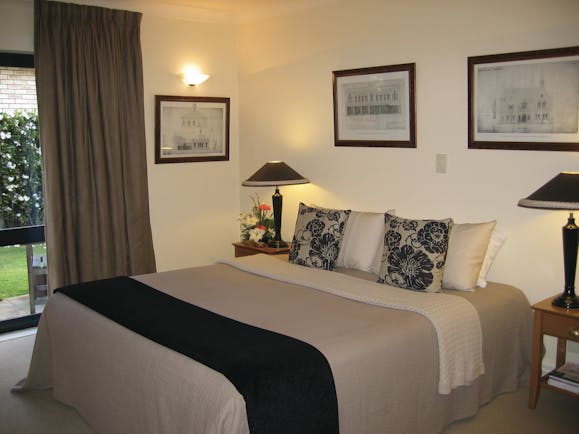 Bedroom with double bed, grey and beige colour scheme and paintings on the wall