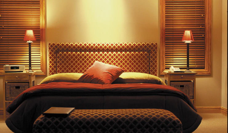 Treetops Lodge Central North Island bedroom with patterned head board and matching ottoman