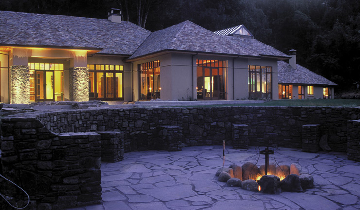 Treetops Lodge Central North Island patio white building with grey roof and terrace around fire pit