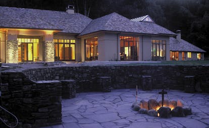 Treetops Lodge Central North Island patio white building with grey roof and terrace around fire pit