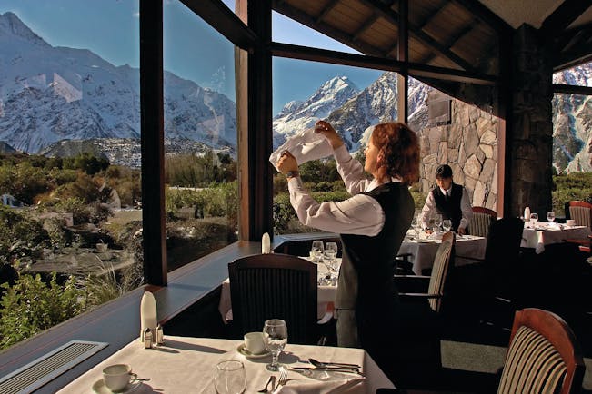 The Hermitage Hotel Central South Island restaurant woman cleaning wine glass in dining room with mountain views