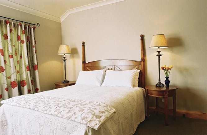 Beckenridge Lodge Hawkes Bay and Napier bedroom with wooden posts and floral curtains