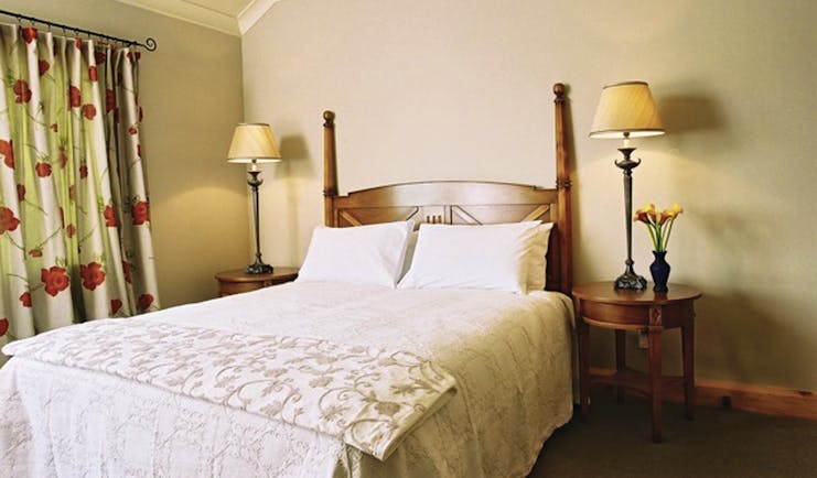 Beckenridge Lodge Hawkes Bay and Napier bedroom with wooden posts and floral curtains