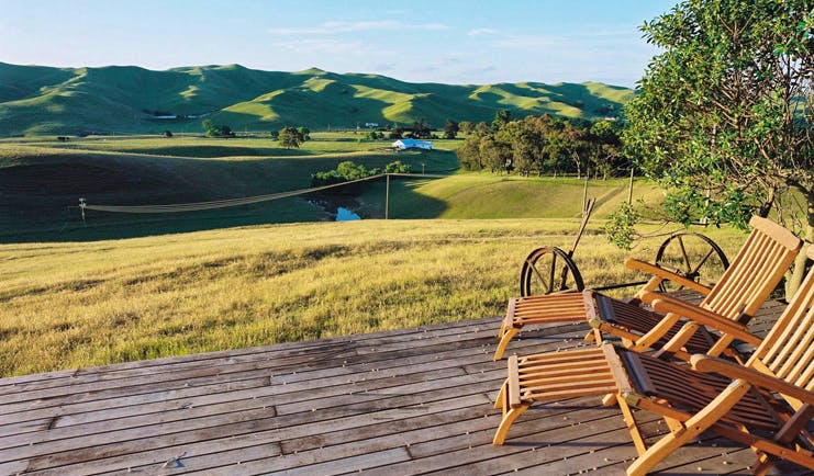 Greenhill Lodge Hawkes Lodge landscape deck two wooden loungers on a deck overlooking rolling green hills