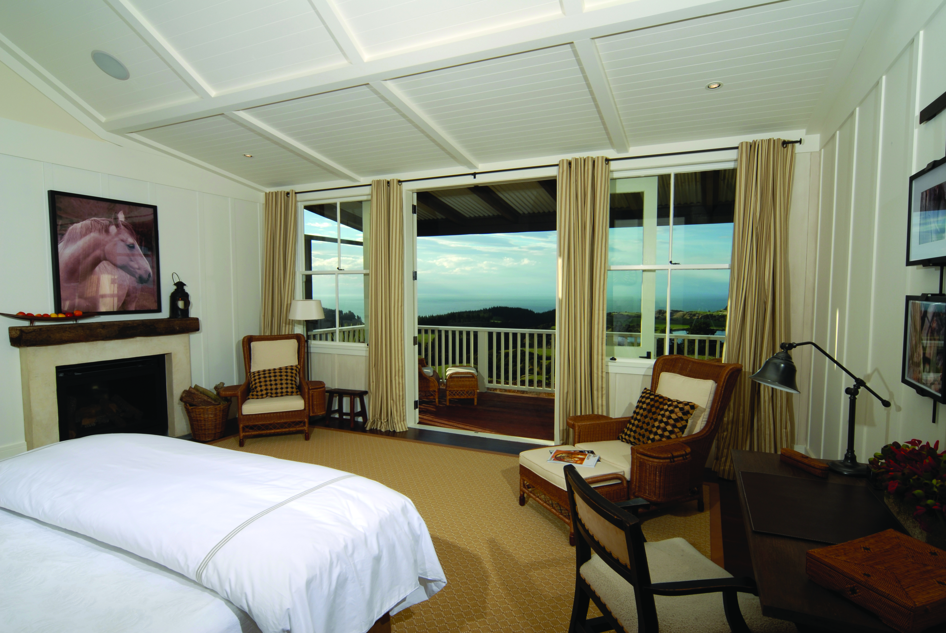 The Farm at Cape Kidnappers Hawkes Bay and Napier suite bedroom with two chairs and patio door to balcony 