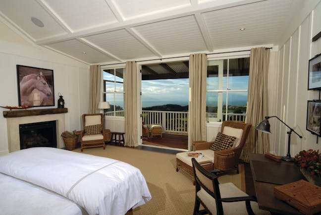The Farm at Cape Kidnappers Hawkes Bay and Napier suite bedroom with two chairs and patio door to balcony 