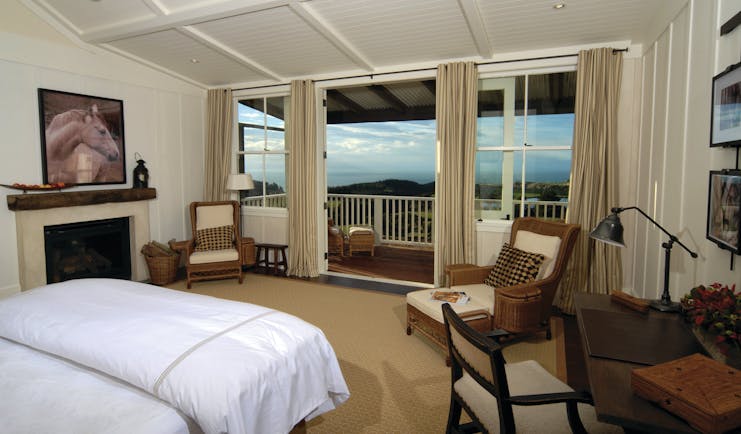 The Farm at Cape Kidnappers Hawkes Bay and Napier suite bedroom with two chairs and patio door to balcony 