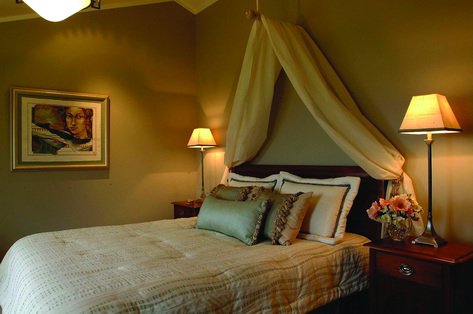 Bedroom with large double bed, bedside tables, lamps and cushions 