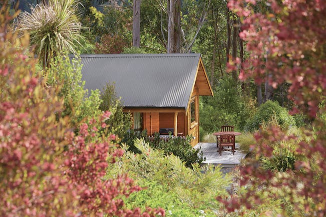The Resurgence ecoLodge Nelson Abel and Tasman exterior wooden chalet with outdoor seating area in a forest
