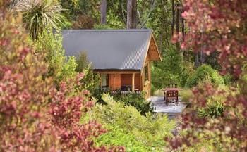 The Resurgence ecoLodge Nelson Abel and Tasman exterior wooden chalet with outdoor seating area in a forest