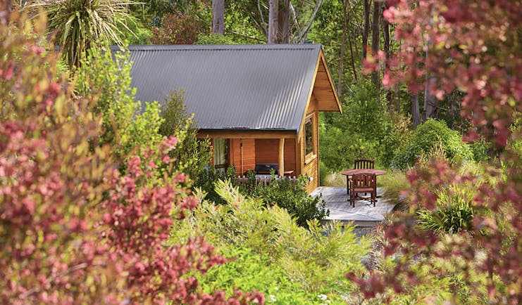 The Resurgence ecoLodge Nelson Abel and Tasman exterior wooden chalet with outdoor seating area in a forest