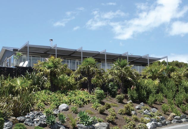 Hotel exterior with green shrubs and bushes around and blue skies 
