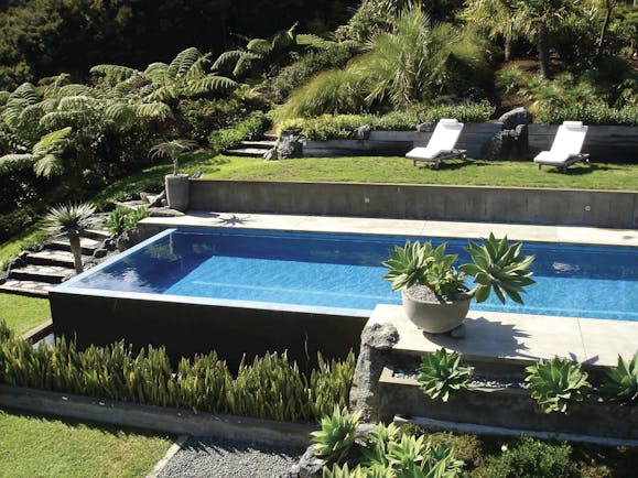 Eagles Nest pool with sun beds around the outside and greenery 