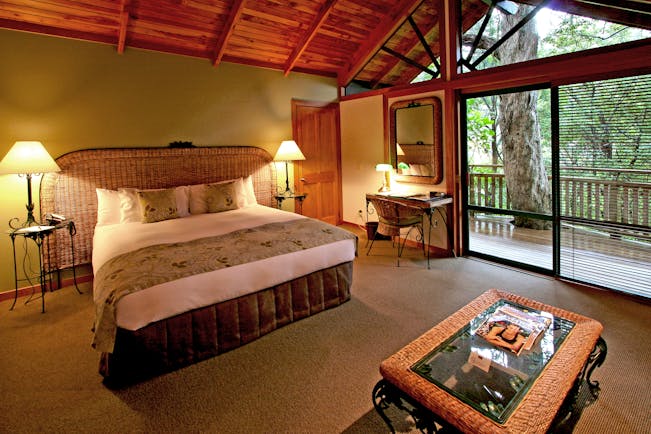 Grand Mercure Puka Park Northlands and Bay of Islands bedroom with wicker head board and balcony with tree