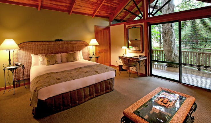 Grand Mercure Puka Park Northlands and Bay of Islands bedroom with wicker head board and balcony with tree