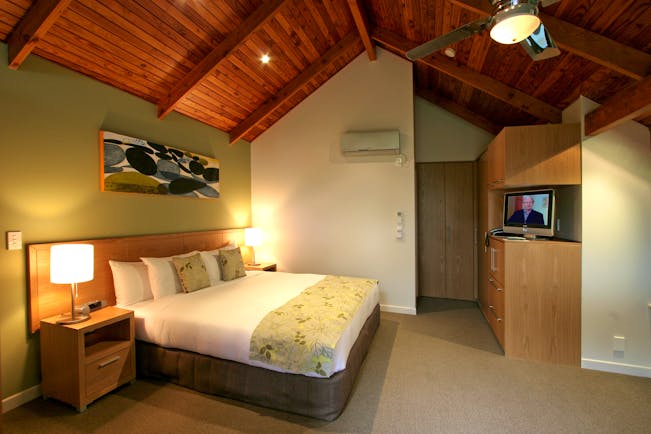 Grand Mercure Puka Park Northlands and Bay of Islands loft bedroom with sofa and balcony with tree