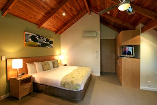 Grand Mercure Puka Park Northlands and Bay of Islands loft bedroom with sofa and balcony with tree