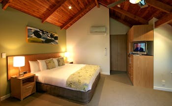 Grand Mercure Puka Park Northlands and Bay of Islands loft bedroom with sofa and balcony with tree