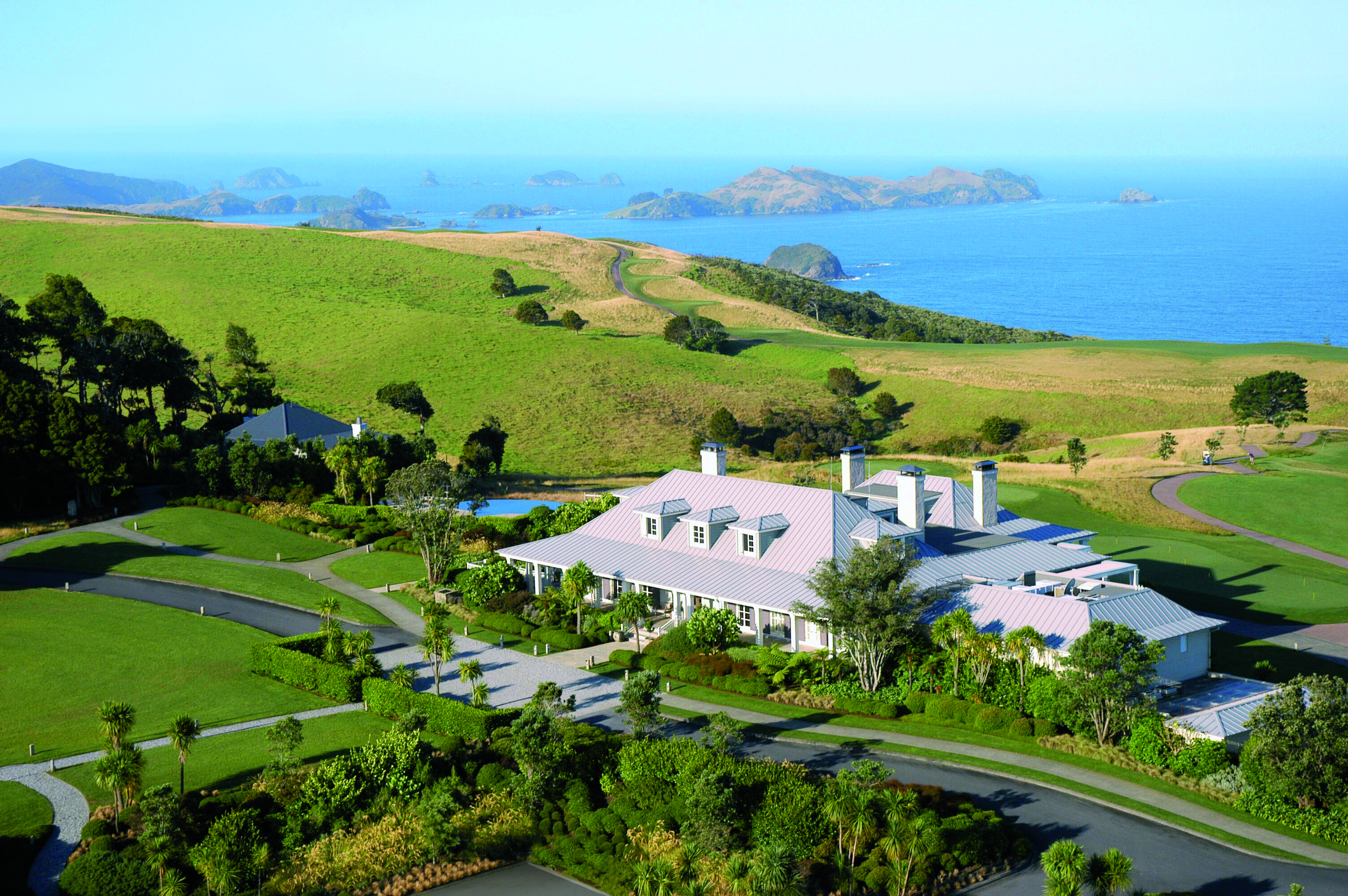 Aerial shot of Kauri Cliffs, hotel building, lawns, sea and coastline