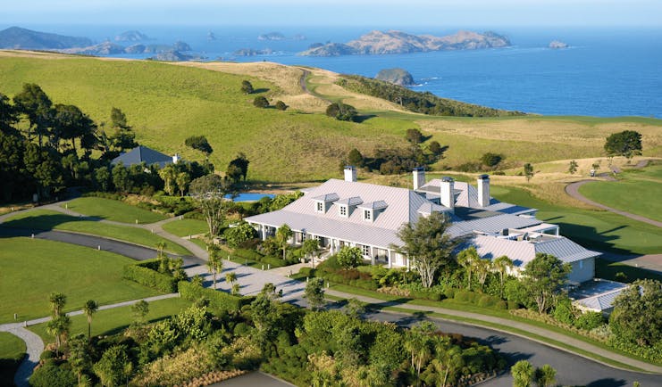Aerial shot of Kauri Cliffs, hotel building, lawns, sea and coastline