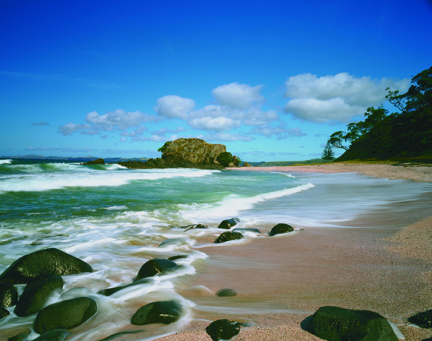 Kauri Cliffs beach, pink sand, blue sea, rocks