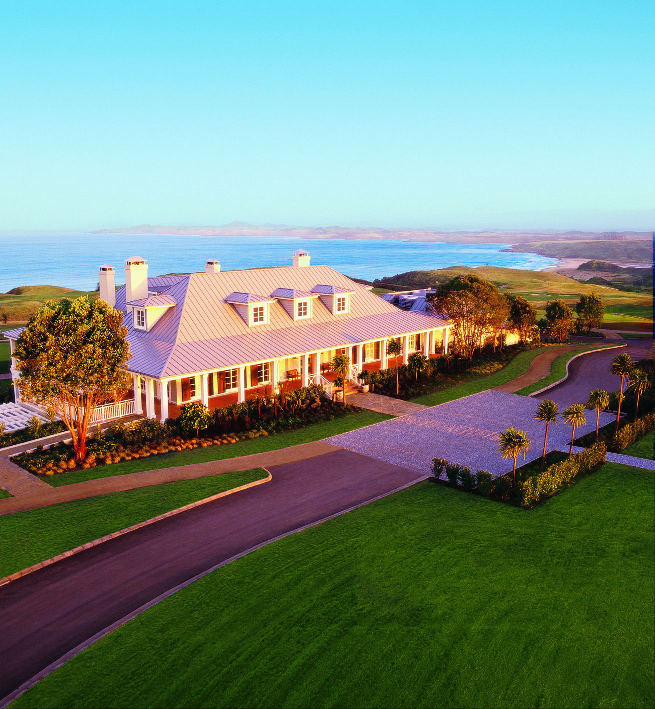 Exterior shot of Kauri Cliffs, hotel building, lawns, sea in backgroubnd