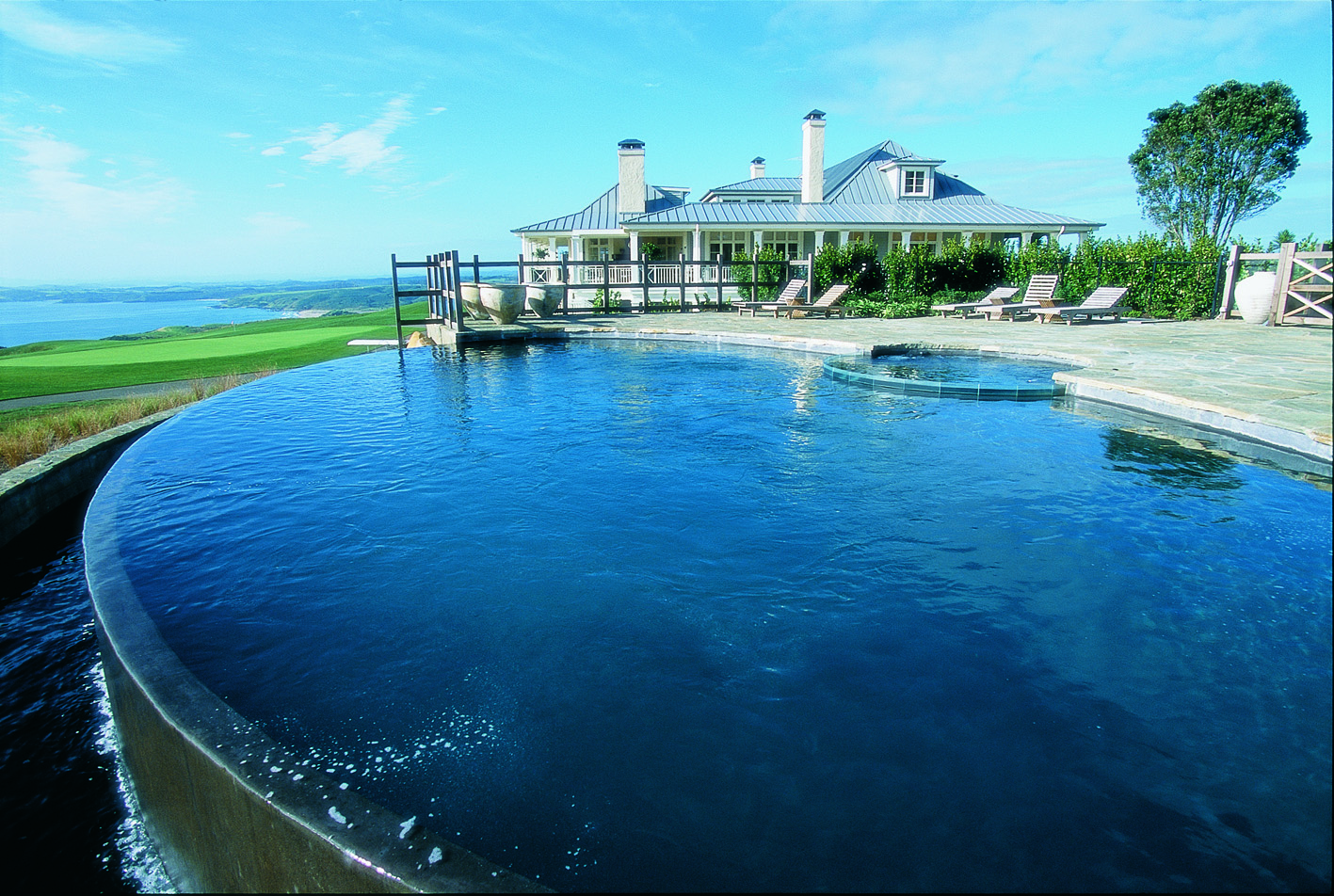 Kauri Cliffs infinity pool, decking, lodge in background, overlooking the sea