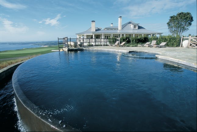 Kauri Cliffs infinity pool, decking, lodge in background, overlooking the sea