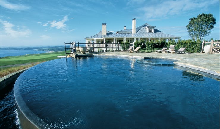 Kauri Cliffs infinity pool, decking, lodge in background, overlooking the sea