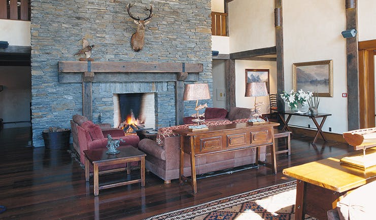 Blanket Bay Otago and Fiordland lounge with sofas and stone fireplace with taxidermy deer head