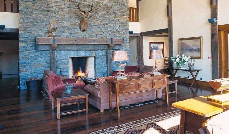 Blanket Bay Otago and Fiordland lounge with sofas and stone fireplace with taxidermy deer head