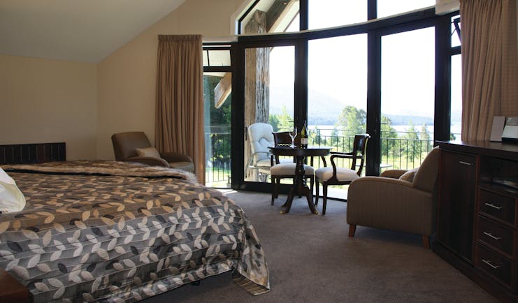 Dock Bay Lodge Otago and Fiordland suite bedroom with floor to ceiling bay window and seating area