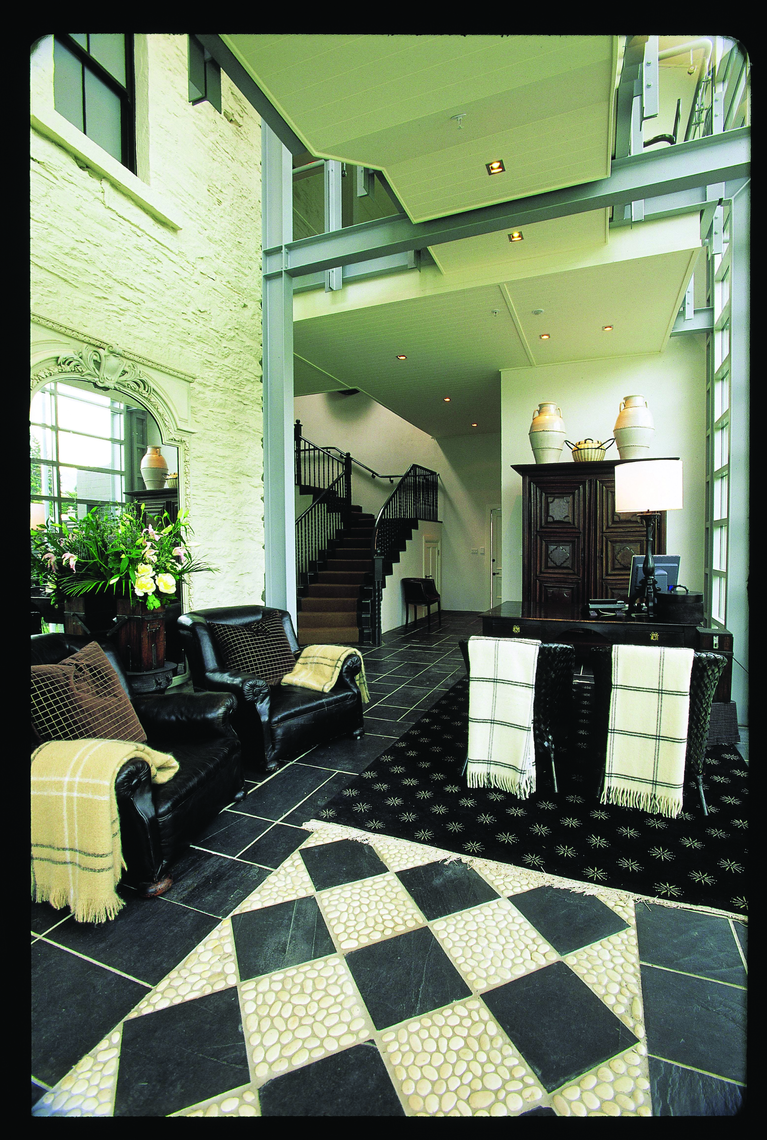 Reception area with desk, black arm chairs and staircase leading upstairs in the distance