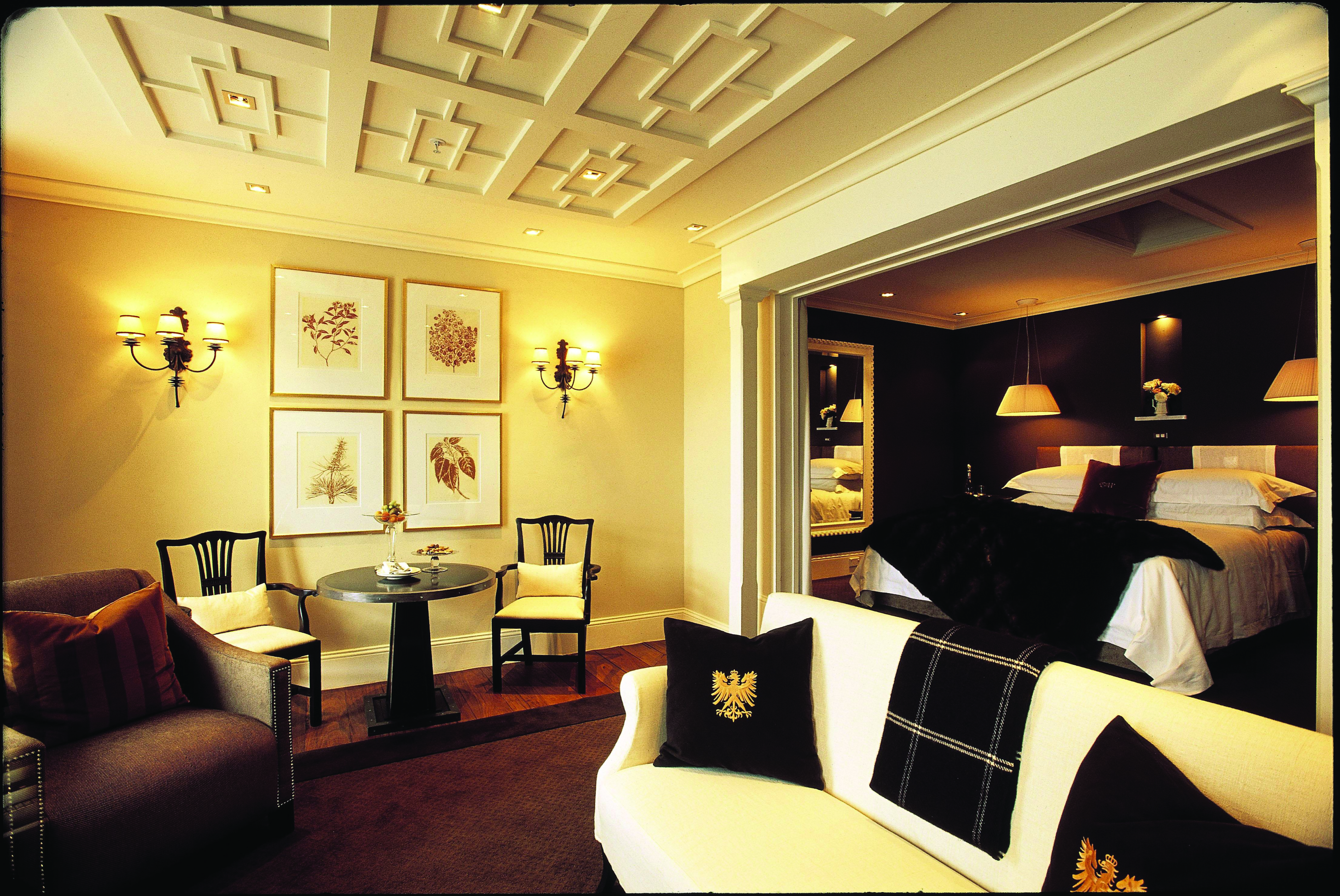 Suite with living room area and bedroom, including a sofa, armchairs, double bed and lamps