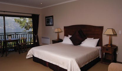 The Hidden Lodge Otago and Fiordland mountain bedroom with table and patio door with mountain and lake view