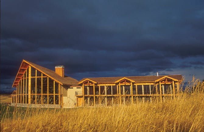 Fiordland Lodge exterior at night with glass and wood pannels surrounding the walls 