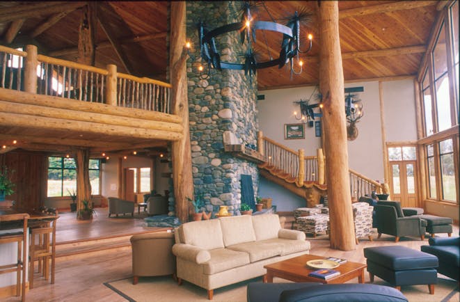 Fiordland Lodge lounge with wooden ceiling and floor, with wooden staircase leading upstairs and sofas