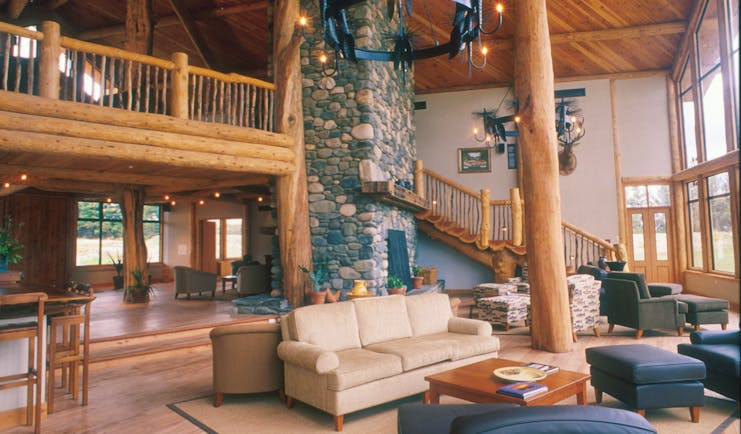 Fiordland Lodge lounge with wooden ceiling and floor, with wooden staircase leading upstairs and sofas