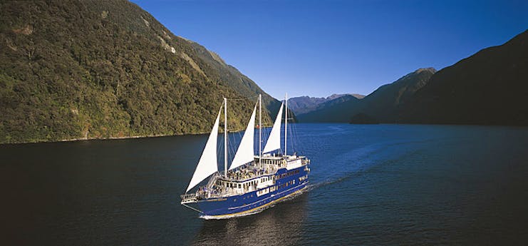 View of ship as it glides in the water amongst the green mountains