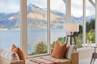 Matakauri Lodge Otago and Fiordland bedroom sofa in front of panoramic windows with mountain and lake view