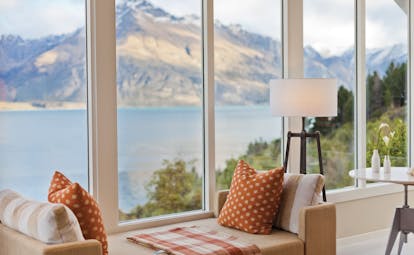 Matakauri Lodge Otago and Fiordland bedroom sofa in front of panoramic windows with mountain and lake view