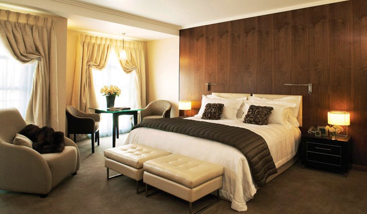 Sofitel Queenstown Otago and Fiordland deluxe king bedroom with armchairs and draped curtains