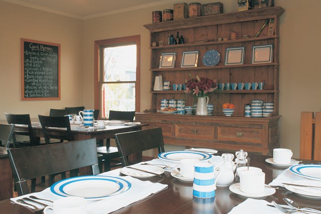 Breakfast dining area with tables and chairs set up and wooden shelves on the wall