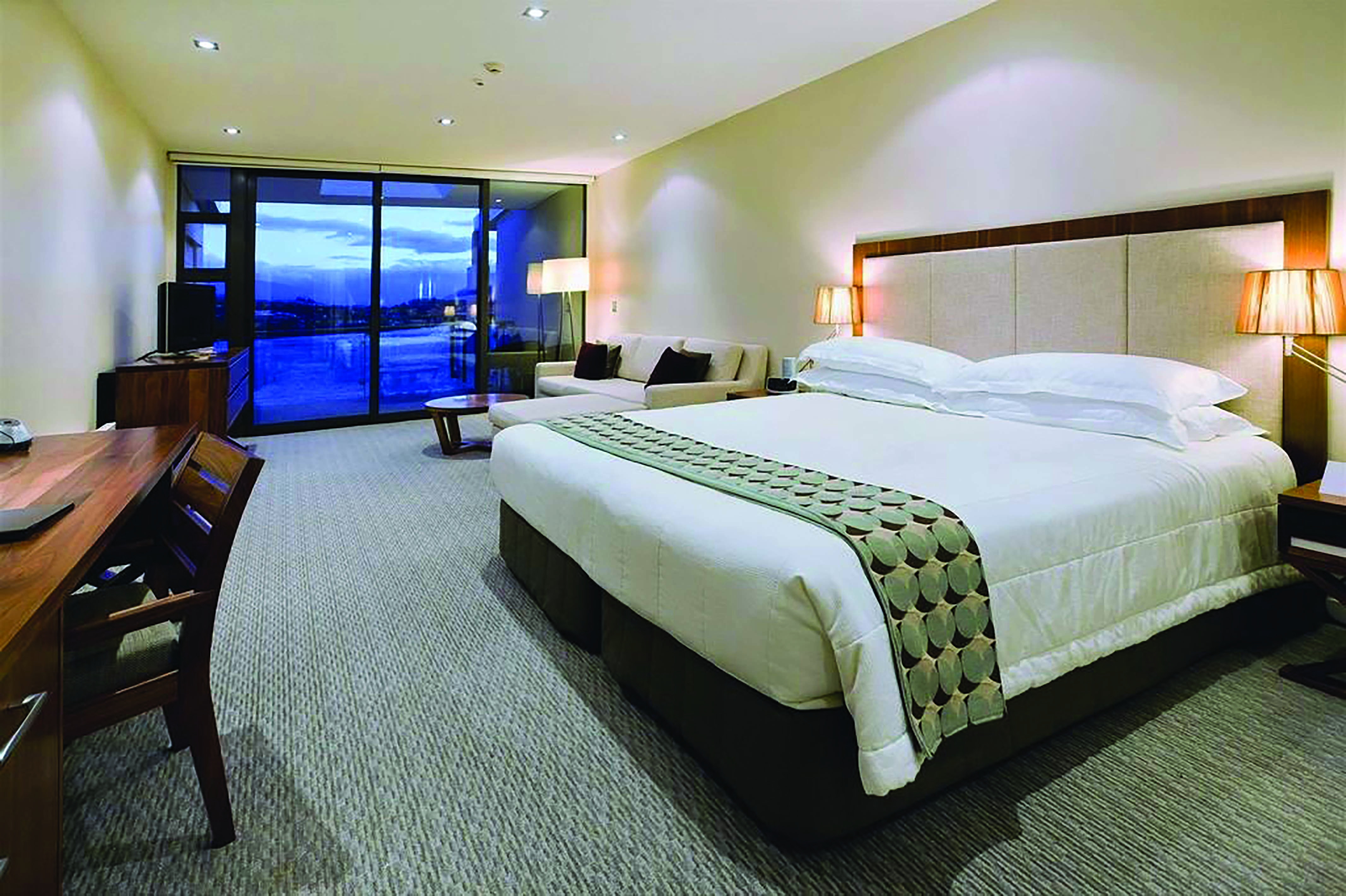 The Rees Hotel Otago and Fiordland bedroom with seating area and large patio door