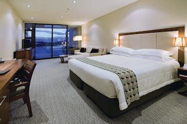 The Rees Hotel Otago and Fiordland bedroom with seating area and large patio door