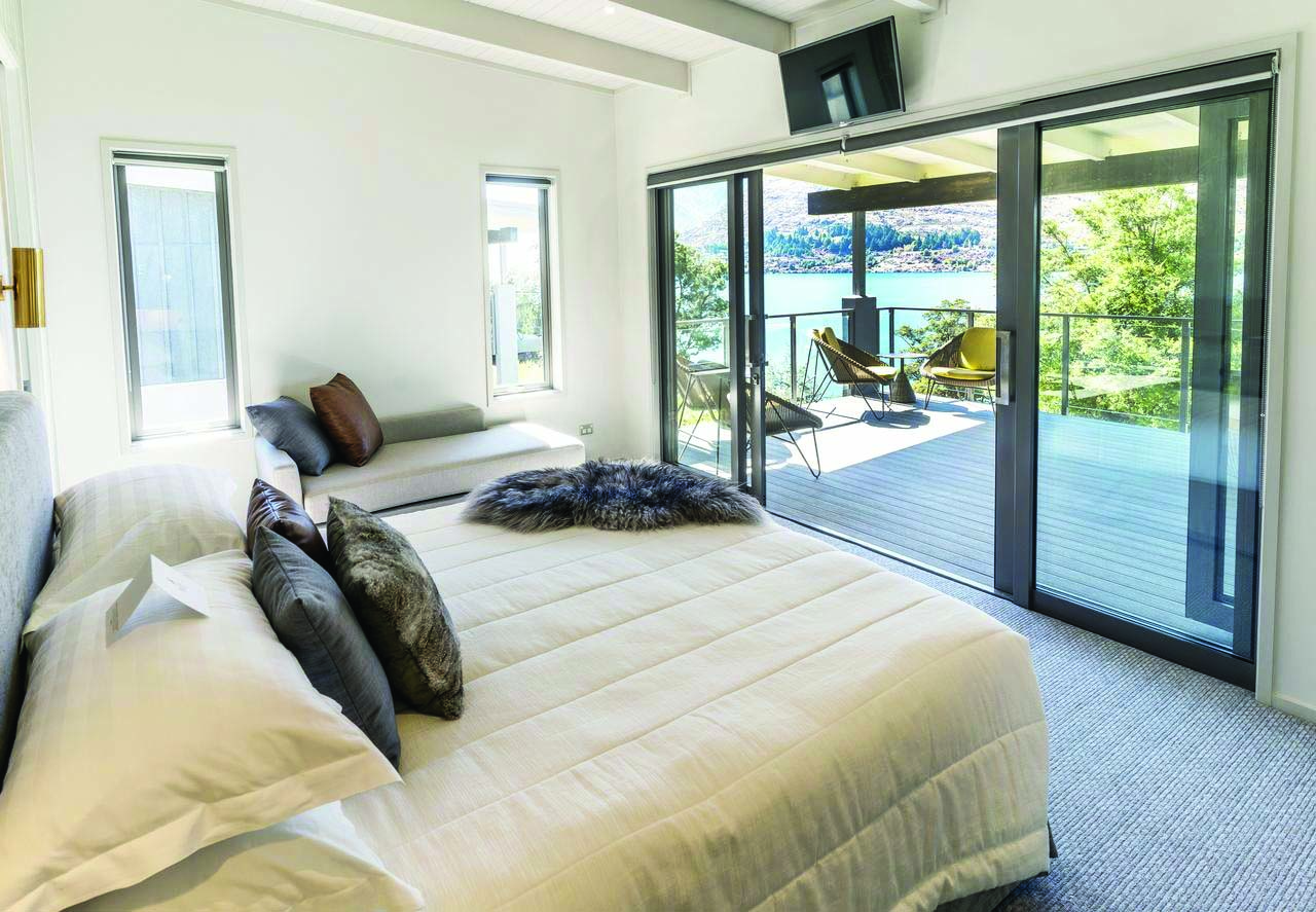 The Rees Hotel Otago and Fiordland bedroom with patio door to decked balcony with mountain lake view