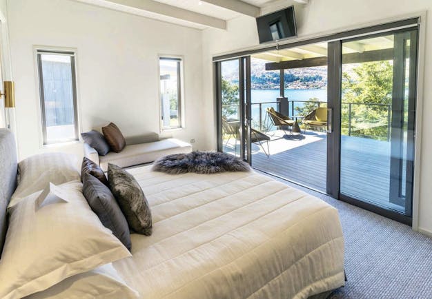 The Rees Hotel Otago and Fiordland bedroom with patio door to decked balcony with mountain lake view