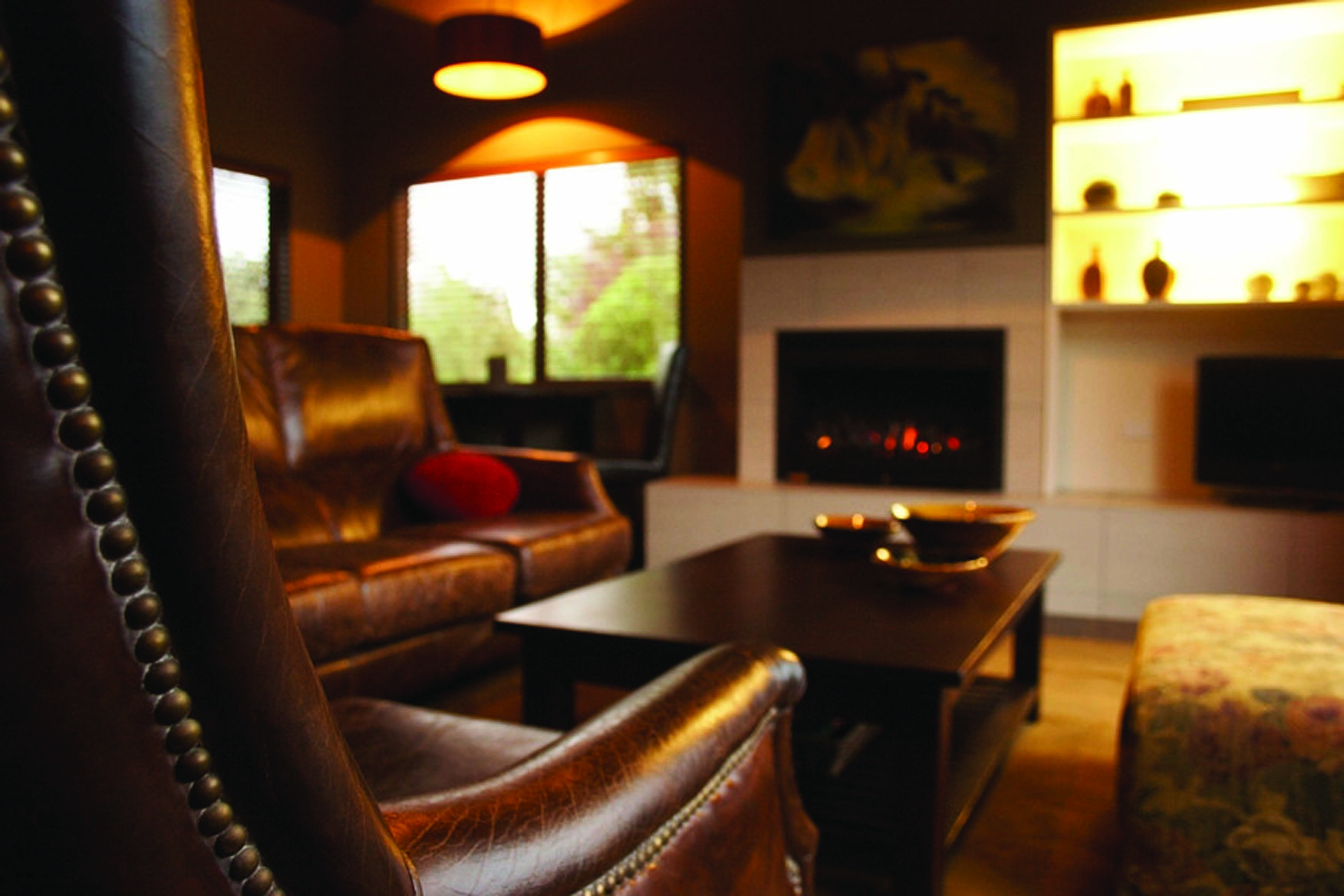 Peppers Parehua Wairarapa sitting room with brown leather chairs and fireplace